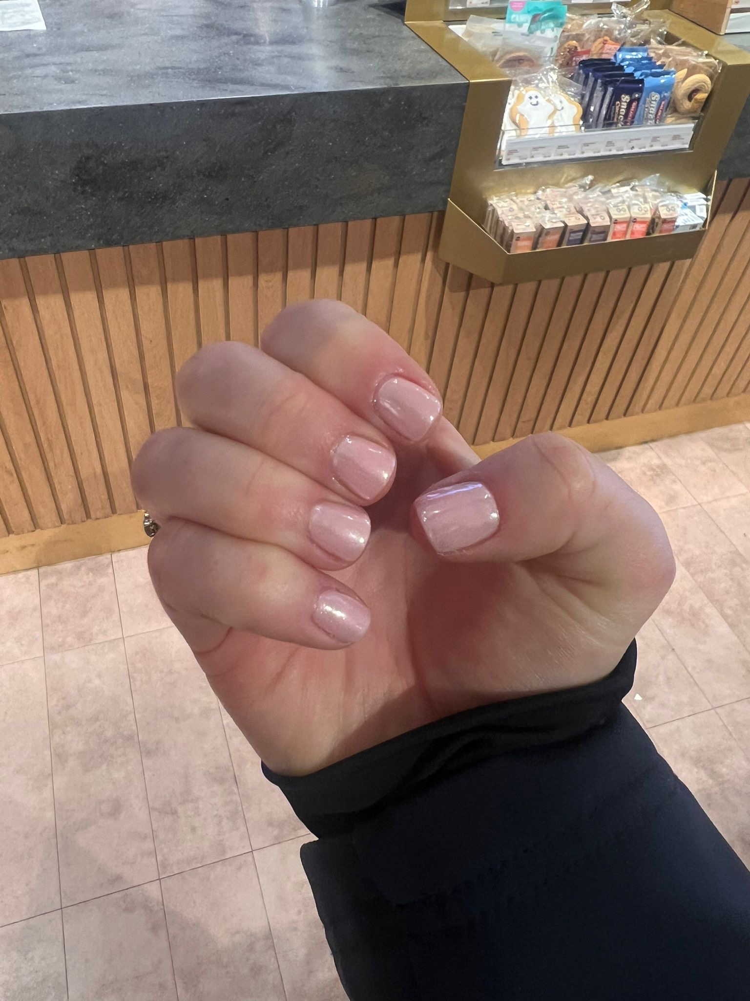 A natural pink gel manicure in the salon, with the nail polish display behind